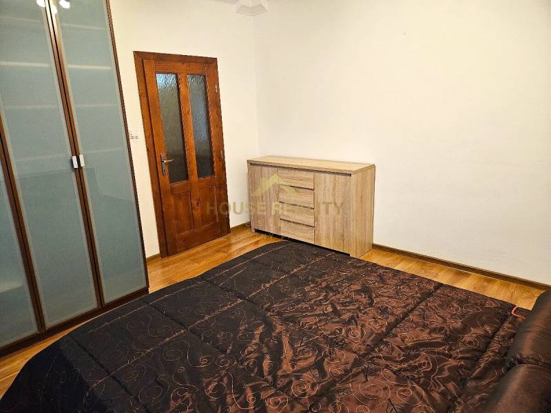 Schlafzimmer in einer 3-Zimmer-Wohnung mit Holzboden, Schrank und Kommode.