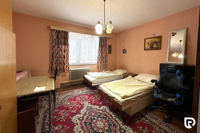 Ein Zimmer in einem Einfamilienhaus mit Teppichboden, zwei Betten und einem Tisch.