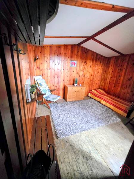 Ein Zimmer in einer Hütte mit Holzverkleidung, ein Sessel, eine Bank, ein Teppich und ein Bett.