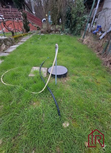 Garten bei der Hütte in Šemša, Rasen mit Brunnen und Schlauch.