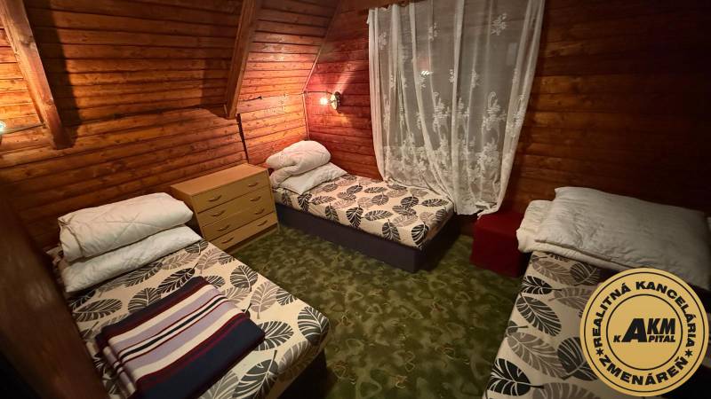 Ein Zimmer in einer Hütte mit Holzverkleidung, drei Betten und einer Kommode.
