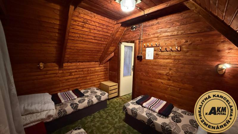 Innenraum einer Hütte mit Holzverkleidung, Betten und Kronleuchter, gemütliche Umgebung zur Entspannung.