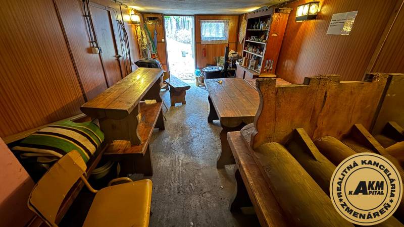 Das Innere der Hütte mit Holztischen und Bänken, Blick auf den Garten.