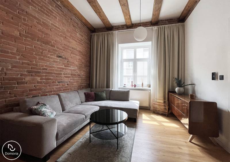 Wohnzimmer in einer 2-Zimmer-Wohnung mit Ziegelwand, Vajnorská, Bratislava, bietet ein bequemes Sofa und einen Couchtisch.