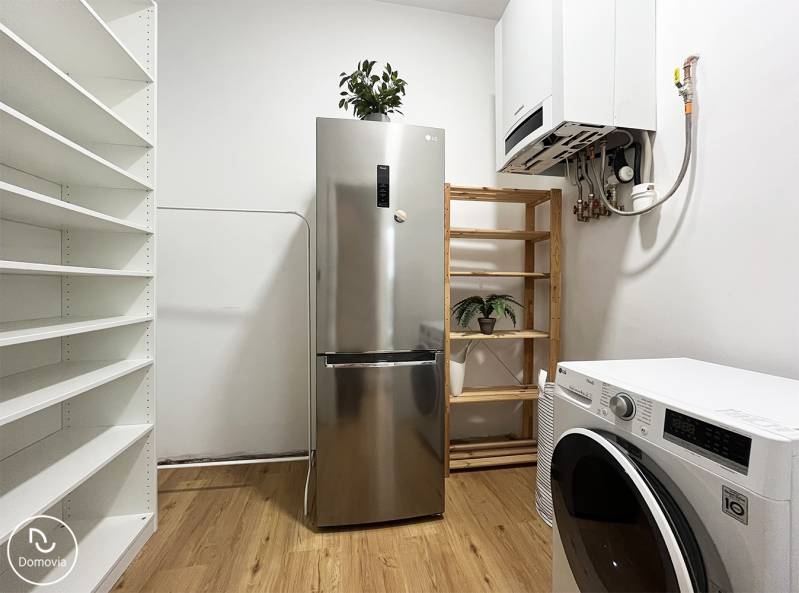 Kühlschrank und Waschmaschine in einer 2-Zimmer-Wohnung in der Vajnorská-Straße, ergänzt durch Regale und Pflanzen.