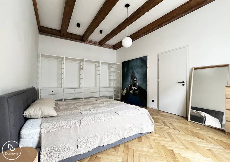 Schlafzimmer in einer 2-Zimmer-Wohnung mit Holzbalken und Spiegel in der Vajnorská-Straße.