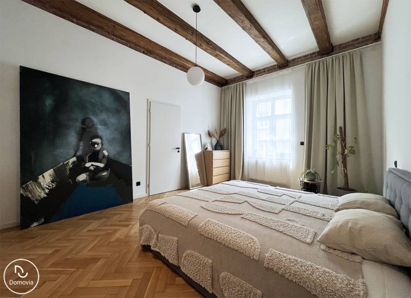 Helles Schlafzimmer mit Holzbalkendecke, Bild an der Wand und dezenter Dekoration.