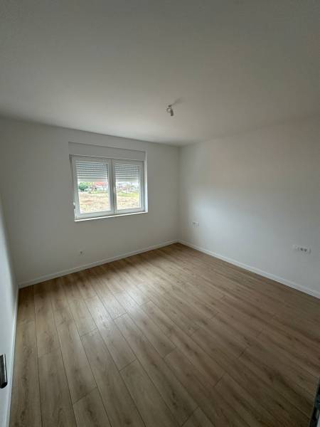 Ein Zimmer in einer 3-Zimmer-Wohnung mit einem Boden in Holzoptik und weißen Wänden.