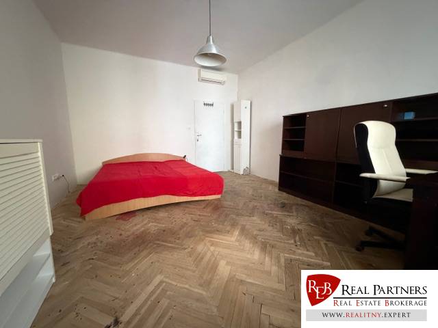 Ein Zimmer mit einem Bett, einem Schreibtisch und einem Boden mit Holzdekor in einer 3-Zimmer-Wohnung.