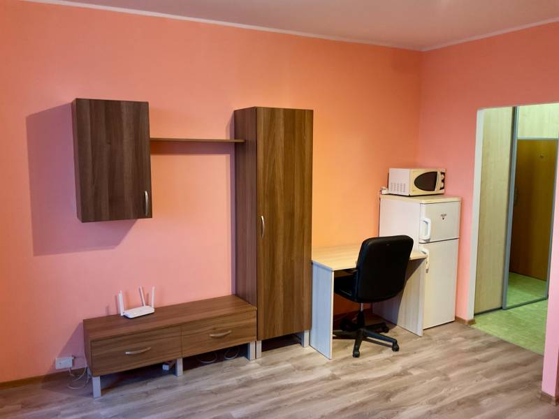 Einzimmerwohnung mit Möbeln, Schreibtisch, Mikrowelle und Holzboden.