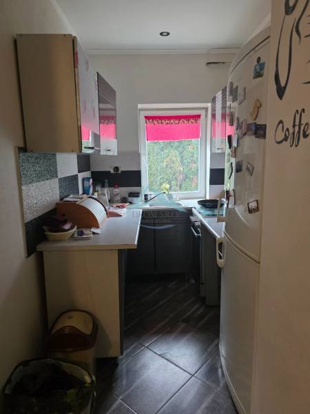 Eine schmale Küche mit schwarz-weißen Schränken und einem großen weißen Kühlschrank in einem Einfamilienhaus.