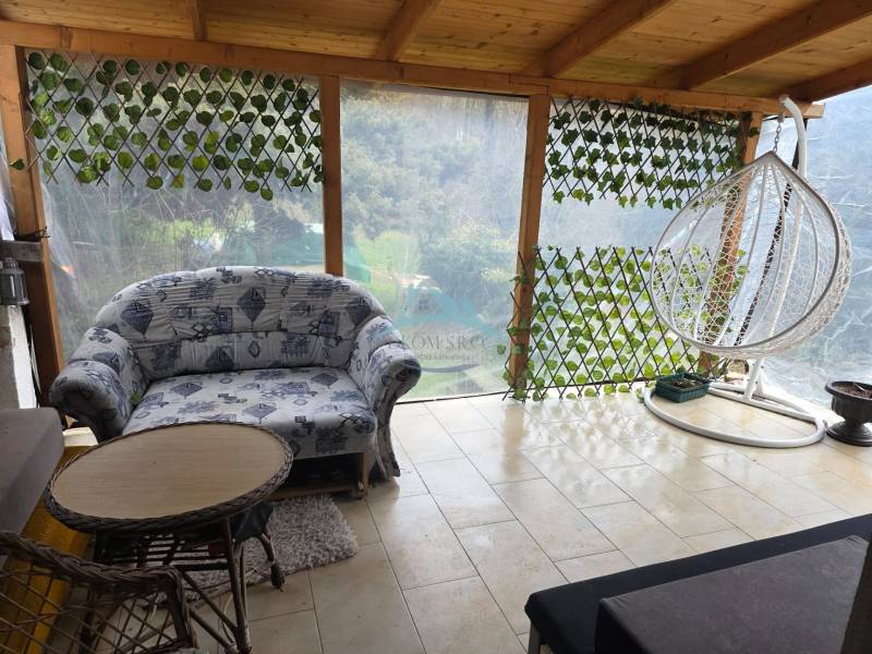 Ein Einfamilienhaus mit einer geräumigen Terrasse, einem bequemen Sofa und einer Schaukel in der Stadt Hont.