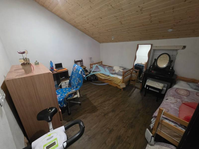 Dachzimmer mit Holzdecke, Boden mit Holzdekor, Bett, Tisch, Spiegel.
