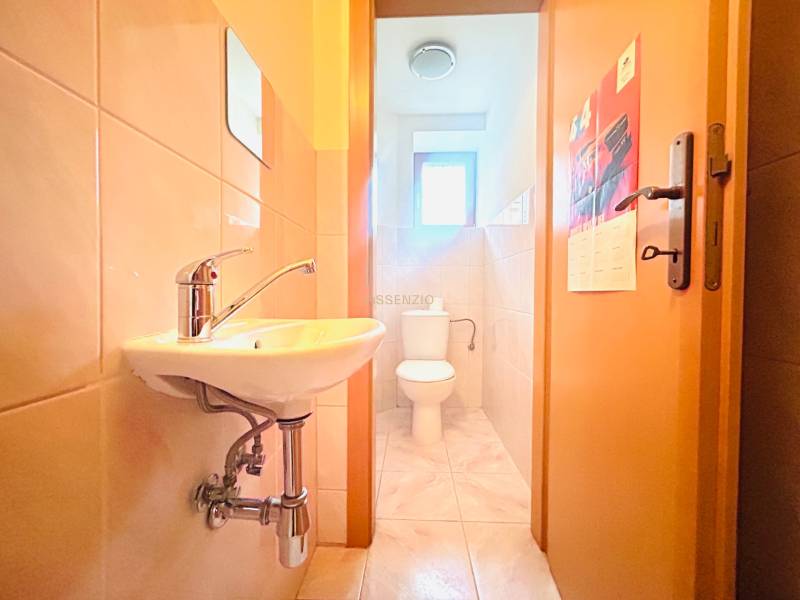 Badezimmer in einem Einfamilienhaus mit Waschbecken, Toilette und hellen Fliesen an den Wänden.