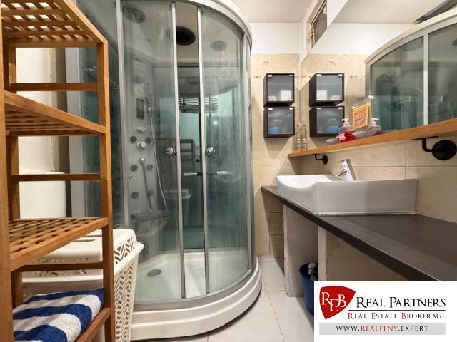 Badezimmer mit Duschkabine und Waschbecken mit Holzdekor, 3-Zimmer-Wohnung.