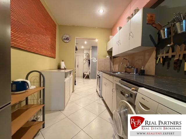 Küche in einer Wohnung mit 5 oder mehr Zimmern mit weißen Schränken und Fliesen, Geräte auf beiden Seiten.