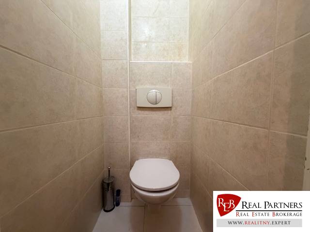 Toilette mit weißen Fliesen und eingebauter Toilette in einer 3-Zimmer-Wohnung.