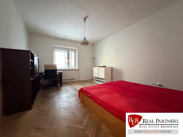 Schlafzimmer in einer 3-Zimmer-Wohnung mit Bett, Schreibtisch und Holzboden.