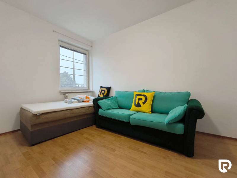 Ein Zimmer mit einem Sofa und einem Bett, Boden mit Holzdekor, Einfamilienhaus.