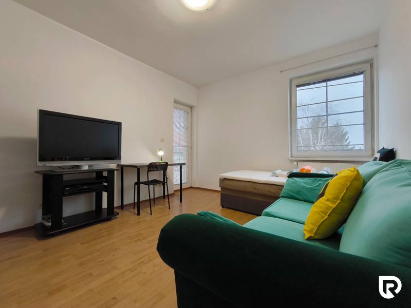 Wohnzimmer in einem Einfamilienhaus mit Sofa, Fernseher, Tisch und Holzboden.