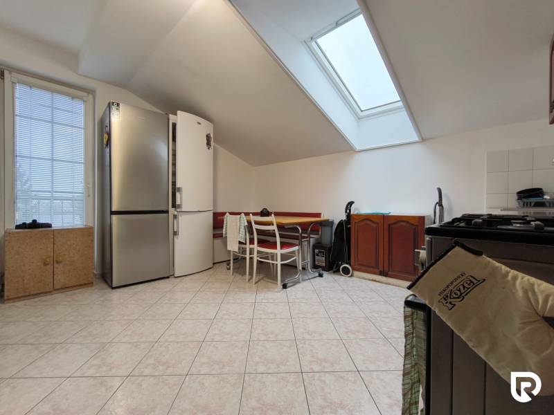 Küche in einem Einfamilienhaus mit schräger Decke, großem Kühlschrank und Esstisch.