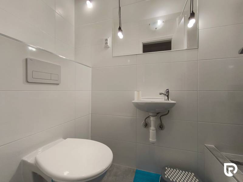 Badezimmer im Einfamilienhaus mit hängendem WC, Waschbecken und Leuchten.