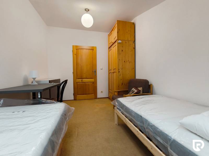 Ein Zimmer in einem Einfamilienhaus mit Betten, einem Tisch, einem Schrank und einem Stuhl.