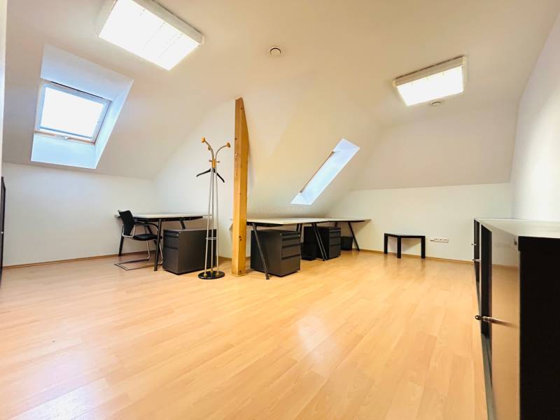 Büros mit Holzboden, Tischen, Stühlen und Dachfenstern.