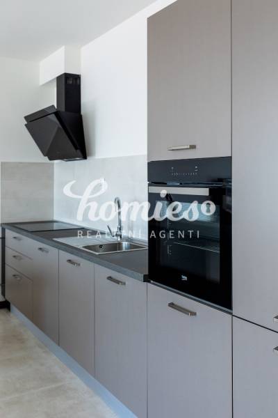 Küche mit linearer Küchenzeile und eingebautem Ofen in einer 3-Zimmer-Wohnung.