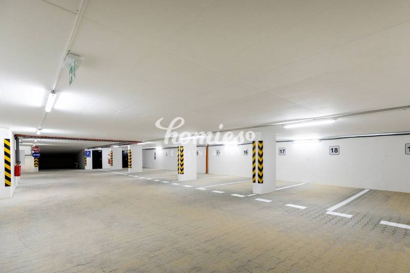 Unterirdischer Parkplatz mit heller Beleuchtung und reservierten Parkplätzen.