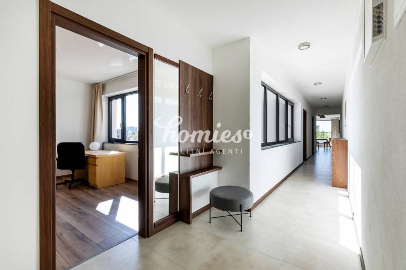 Ein heller Flur mit einem Arbeitszimmer und einem Boden mit Holzdekor in einer 3-Zimmer-Wohnung.