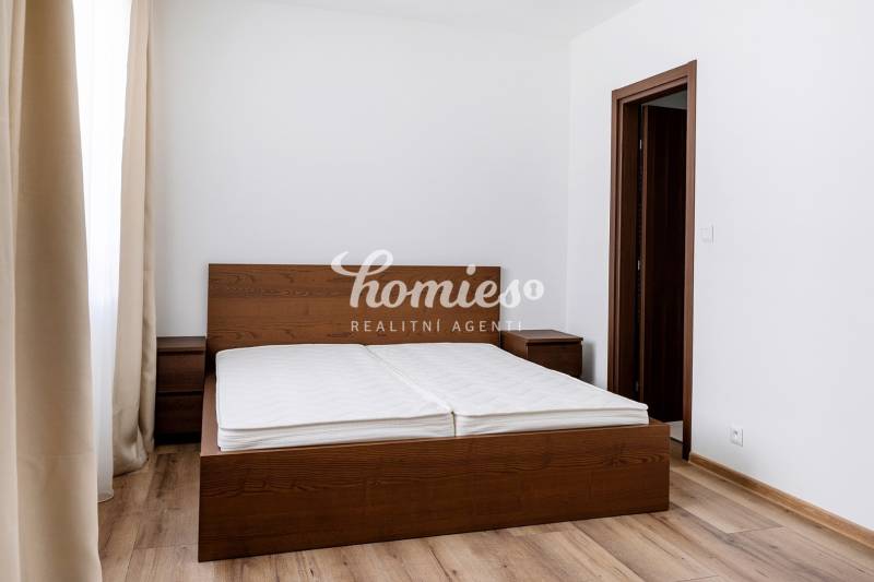 Schlafzimmer in einer 3-Zimmer-Wohnung mit einem Bett aus dunklem Holz und einem Boden mit Holzdekor.