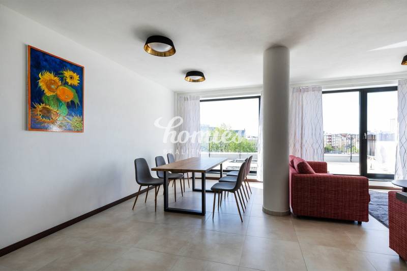 Esszimmer in einer 3-Zimmer-Wohnung mit einem Bild von Sonnenblumen, einem Boden in Holzoptik und Blick auf die Terrasse.