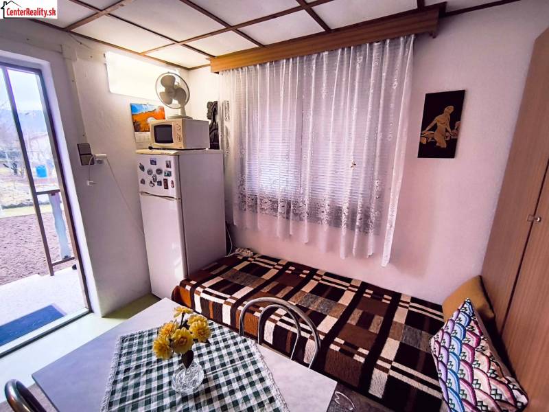 Innenraum der Hütte mit Kühlschrank, Sofa, Tisch und Blick in den Garten.