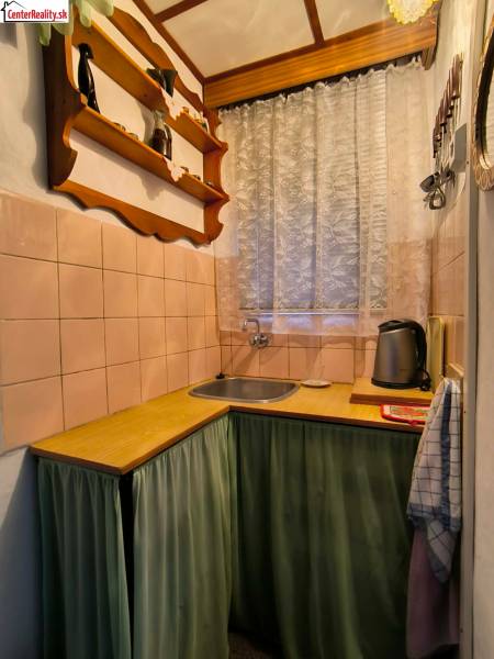 Küche in einer Hütte mit Holzdekor, Regal und Vorhang am Fenster.