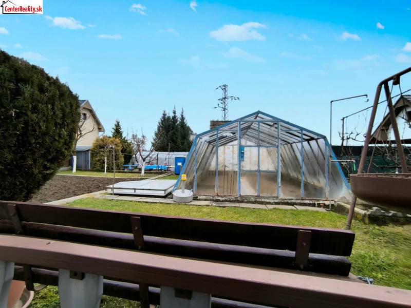 Ein Garten in Partizánske mit einem Folientunnel, Gras und einem kleinen Beet.