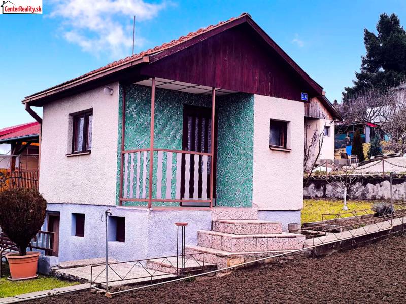 Ein Ferienhaus in Partizánske mit Parkgestaltung, grüner Fassade und einer Treppe zur Terrasse.