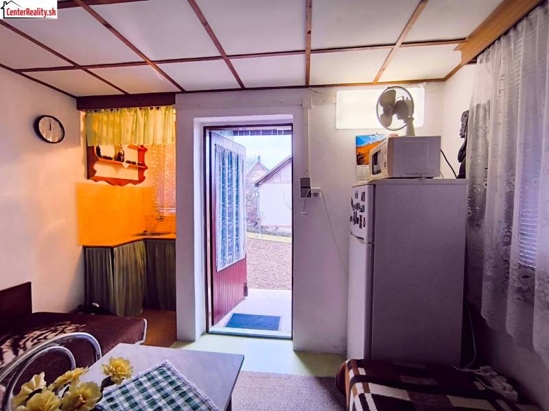 Das Innere der Hütte mit Küche, Sofa und offenen Türen zum Garten.