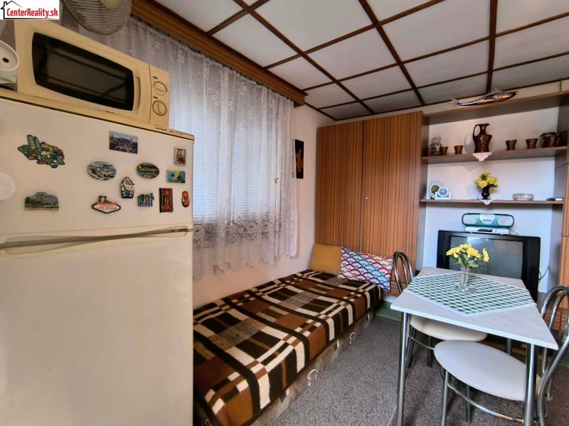 Eine kleine Küche in der Hütte mit Holzelementen, einem Esstisch und einem Kühlschrank.