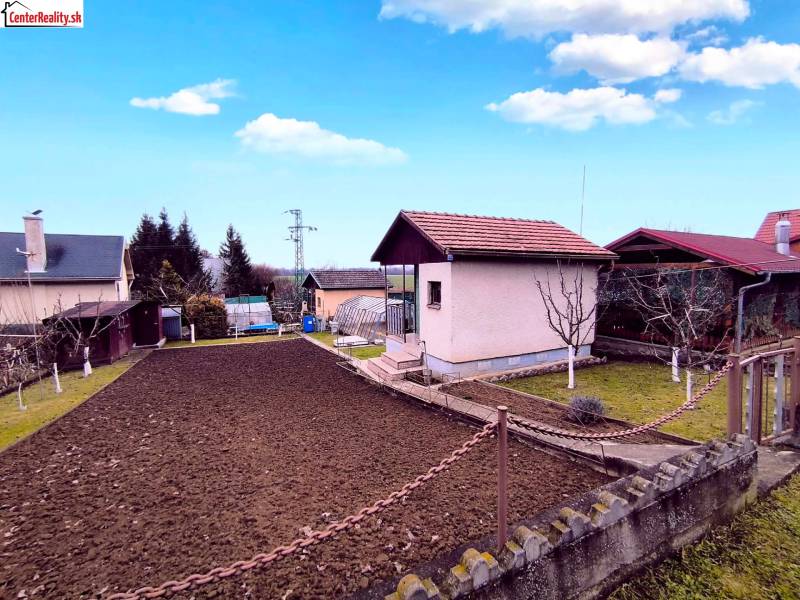 Das Äußere der Hütte in Partizánske mit gepflegtem Garten, Rasen und Blumenbeet.