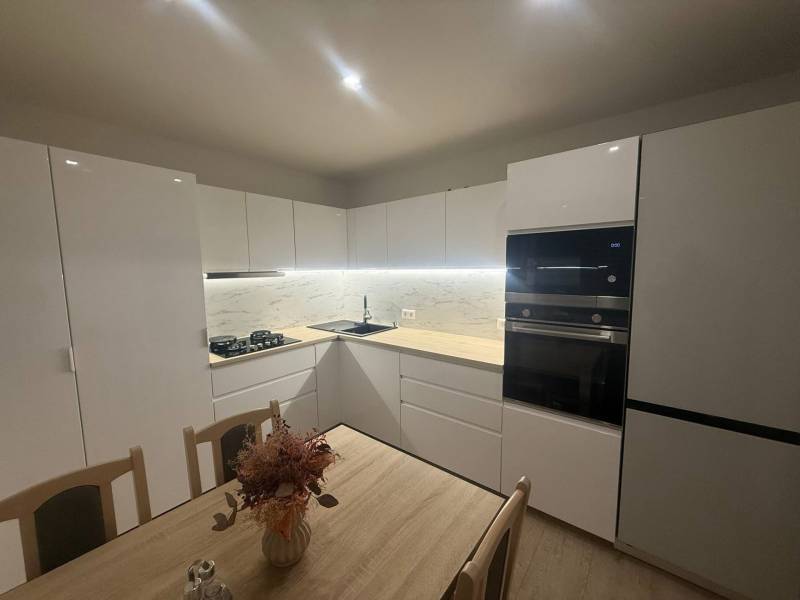 Moderne Küche in einer 3-Zimmer-Wohnung mit weißen Schränken und Marmorverkleidung.