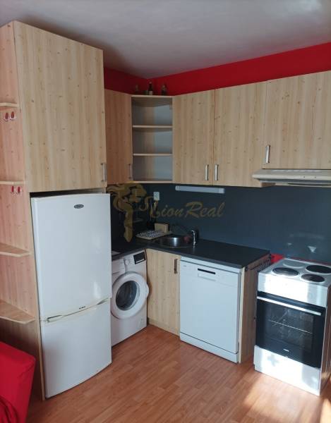 Küchenecke mit Holzdekor und Geräten in einer Einzimmerwohnung.