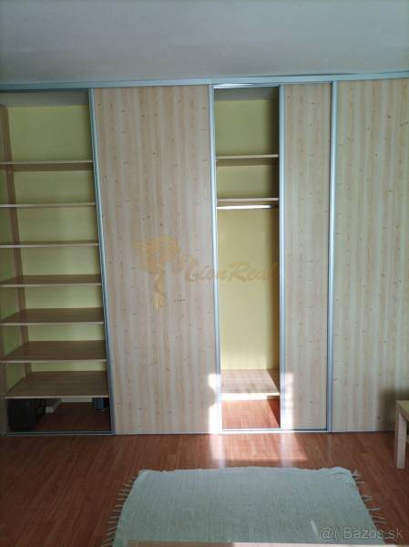 Einbauschrank mit Schiebetüren und Regalen, Boden mit Holzdekor in einer Einzimmerwohnung.