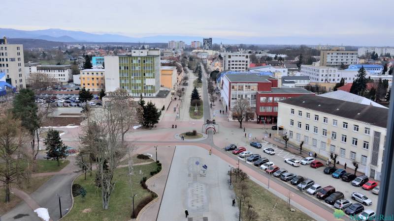 Blick auf die Büros am Freiheitsplatz in Michalovce mit geparkten Autos und Fußgängern.