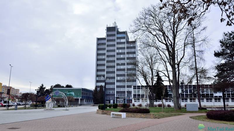 Büros am Freiheitsplatz in Michalovce, ein hohes Gebäude mit Fenstern und Bäumen in der Umgebung.