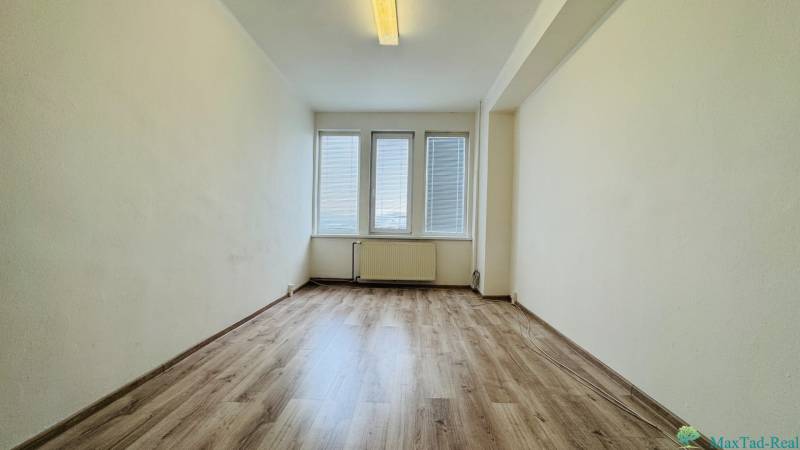 Ein Büro mit großen Fenstern und einem Boden in Holzoptik.