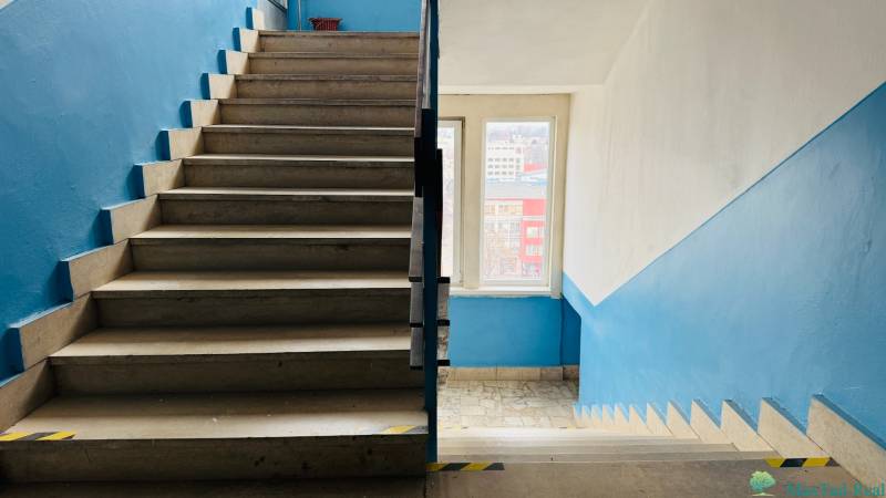 Treppe im Innenbereich des Büros mit blauen Wänden und hellen Fliesen.