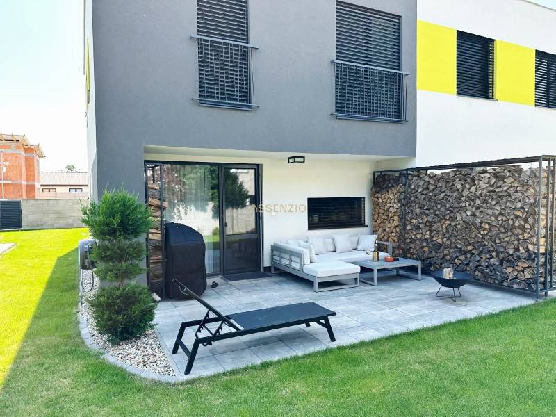 Einfamilienhaus in Rovinka mit Terrasse, Garten, Holzverkleidung und Sitzgelegenheit im Freien.