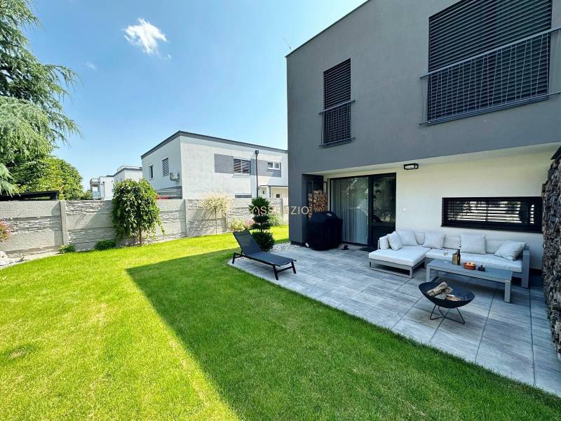 Einfamilienhaus in Rovinka mit Terrasse, grünem Rasen und Außenbereich zum Sitzen.