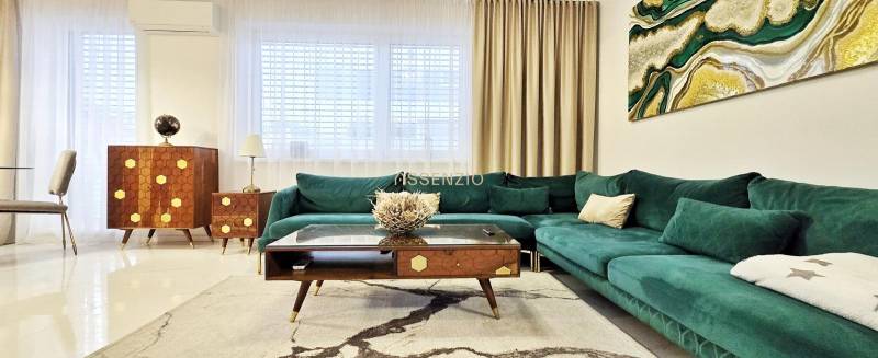 Ein Einfamilienhaus mit einem Sofa in Grüntönen, Holzmöbeln und Kunst an der Wand.